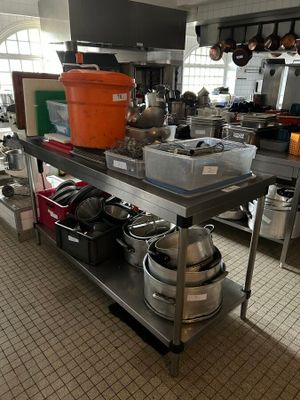many pots and pans on a metal shelf in the kitchen