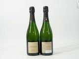 deux bouteilles de champagne posées l'une à côté de l'autre sur une surface blanche