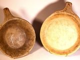 pair of brown ceramic bowls sitting next to each other on a white surface