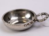 a small silver bowl with a handle on a white surface