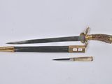 two knifes with gold and black handles on a white surface