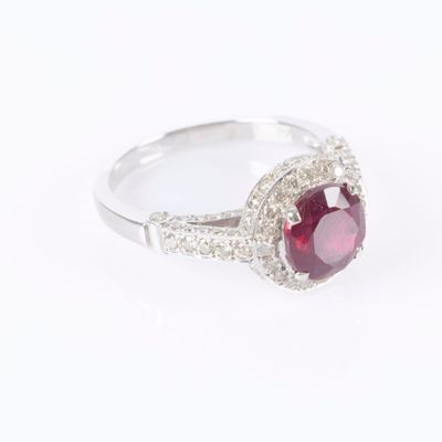 a close up of a ring with a red stone surrounded by white diamonds