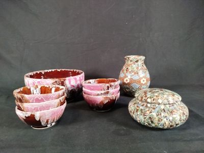 five bowls and a vase sitting on a black background