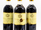 three bottles of wine sitting next to each other on a white surface