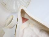 un sac blanc orné d'un triangle rouge, à côté d'une tasse et d'une soucoupe