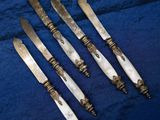 four antique silverplated knives on a blue cloth