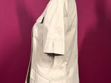 beige jacket on a mannequin stand against a red wall