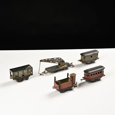 cinq petits trains miniatures posés sur une surface blanche, sur fond noir