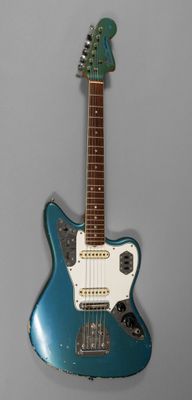 une guitare électrique au corps bleu posée sur une surface grise