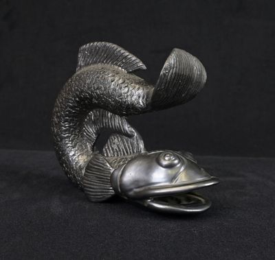 a silver statue of a fish on a black background