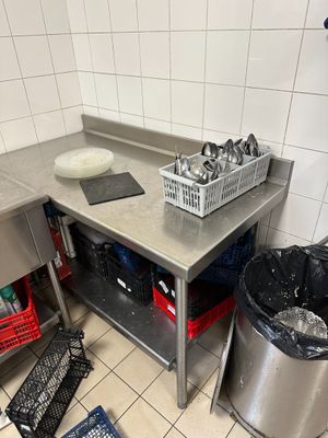 une cuisine équipée d'un évier, d'un plan de travail et d'une poubelle