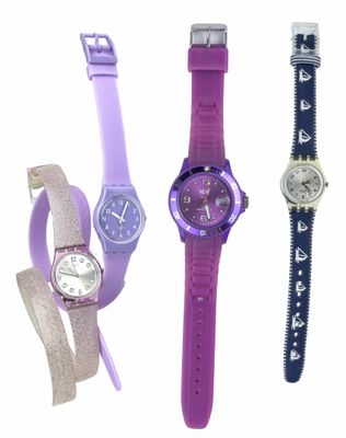 Quatre montres de couleurs différentes sont alignées sur une surface blanche