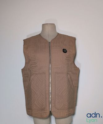 gilet matelassé beige avec un écusson noir sur le devant