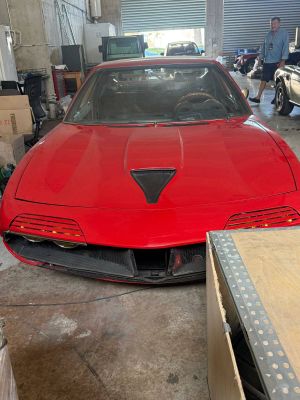 a red sports car parked in a garage with other cars in the background