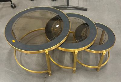 trois tables avec un plateau en verre et un piètement doré dans une pièce