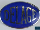 enseigne Delage ovale bleue avec un lettrage argenté sur fond blanc