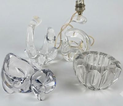 trois figurines en cristal posées sur une table à côté d'une ampoule