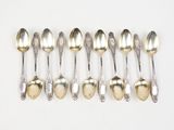 six silver spoons are lined up in a row on a white surface