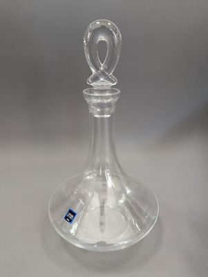une bouteille en verre transparent vide, sur laquelle est collé un autocollant bleu