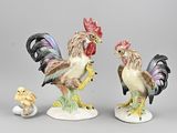 deux figurines représentant des coqs et un poussin posées sur une table