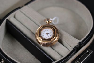 a gold pocket watch in a case on a black surface