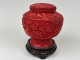 a red vase sitting on a stand with a white background