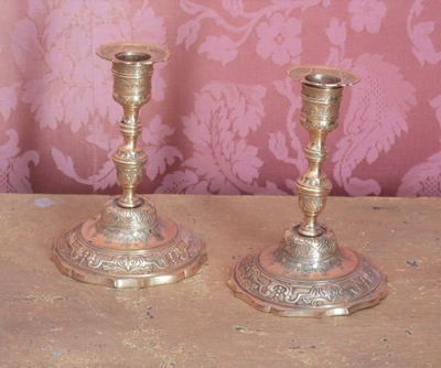 deux bougeoirs en argent posés sur une table en bois