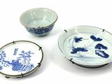 three blue and white plates and a bowl on a white surface