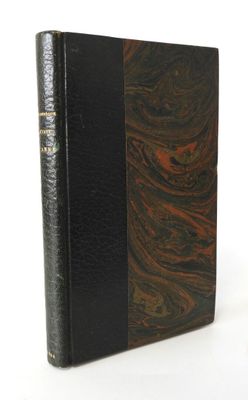 an old book with a black cover sitting on a white surface