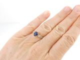 a woman ' s hand holding a ring with a blue stone on it