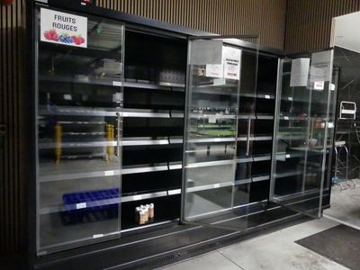 de nombreux réfrigérateurs vides dans un magasin, sur lesquels sont apposées des affiches