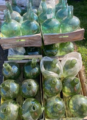 de nombreuses bouteilles en verre vert posées dans une caisse posée par terre
