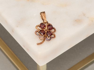 a gold plated pendant with a flower on a marble table