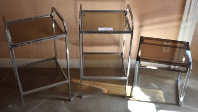 three glass shelves in the corner of a room next to a chair