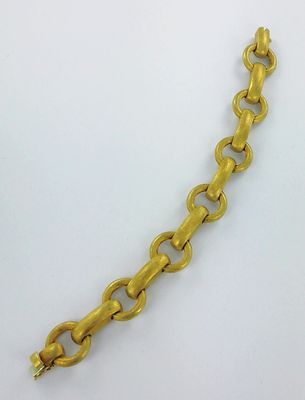 gros plan d'un bracelet en chaîne en or sur une surface blanche