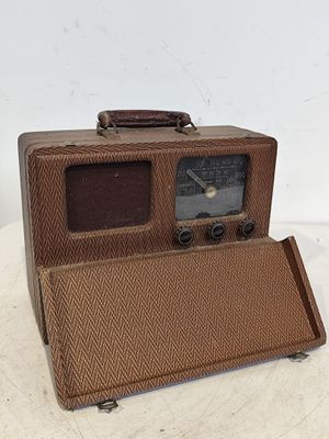 une vieille radio marron posée sur une table blanche