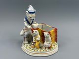 une figurine représentant un garçon et deux chiens posée sur une table