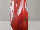 a red penguin statue on display in front of a concrete wall