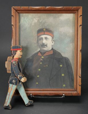 une vieille photo représentant un homme en uniforme militaire à côté d'un soldat de plomb