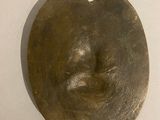 a metal object with a face on it hanging on a wall