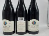 trois bouteilles de vin rouge sont alignées sur une table