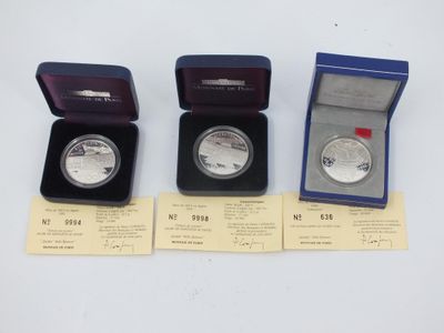 three silver coins are in a blue box on a white surface
