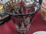 a glass vase sitting on a table with a clock in the background