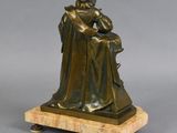 an image of a bronze statue of a man sitting on a marble base