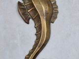 a brass seahorse that is sitting on a white surface