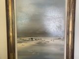 an oil painting of a beach scene in a gold frame on a black table