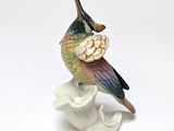 a figurine of a bird sitting on a flower