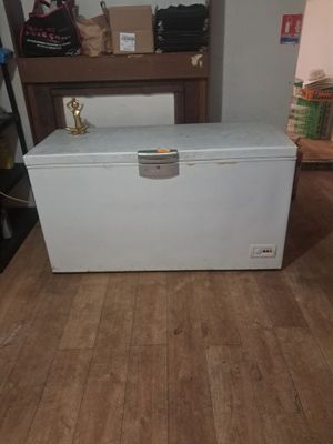 un congélateur coffre blanc posé sur un plancher en bois