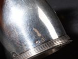 a silver vase that is sitting on a black table