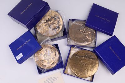 Plusieurs pièces d'or se trouvent dans une boîte bleue posée sur une surface blanche
